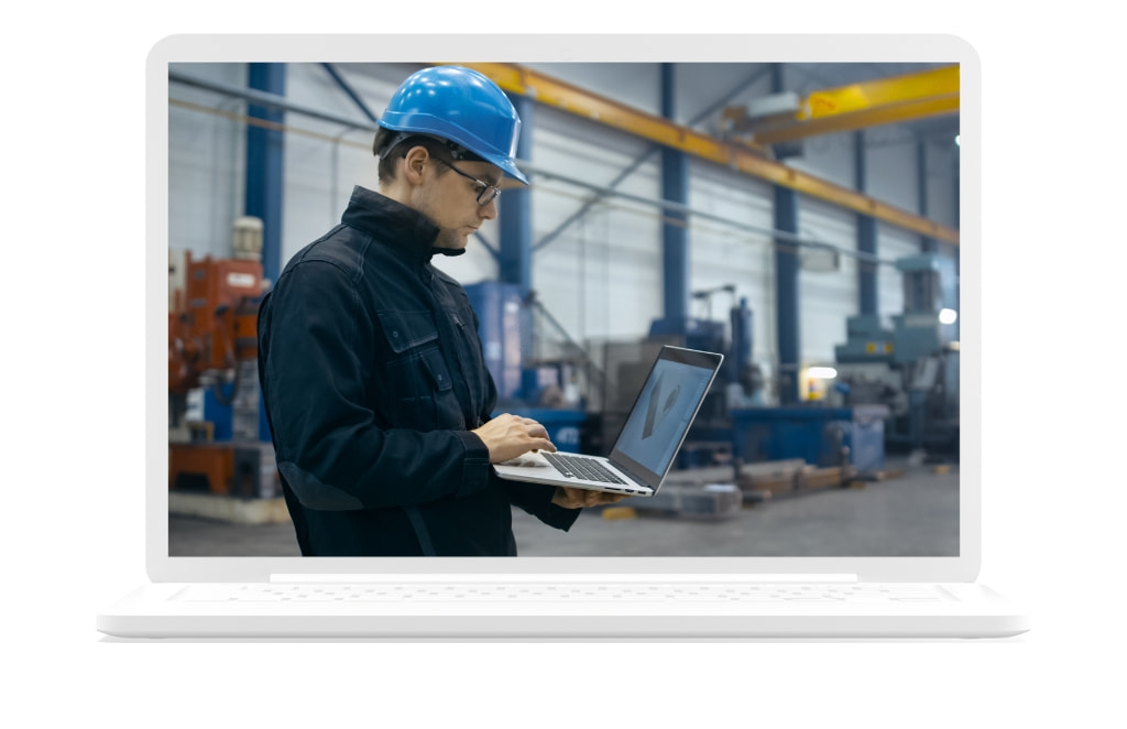 Mann arbeitet an einem Laptop in einer Fertigungshalle | SPI GmbH